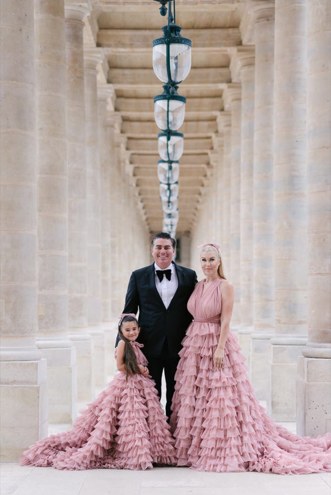 Elegant family of three in matching pink gowns in a Parisian colonnade for a family portrait by SabShots