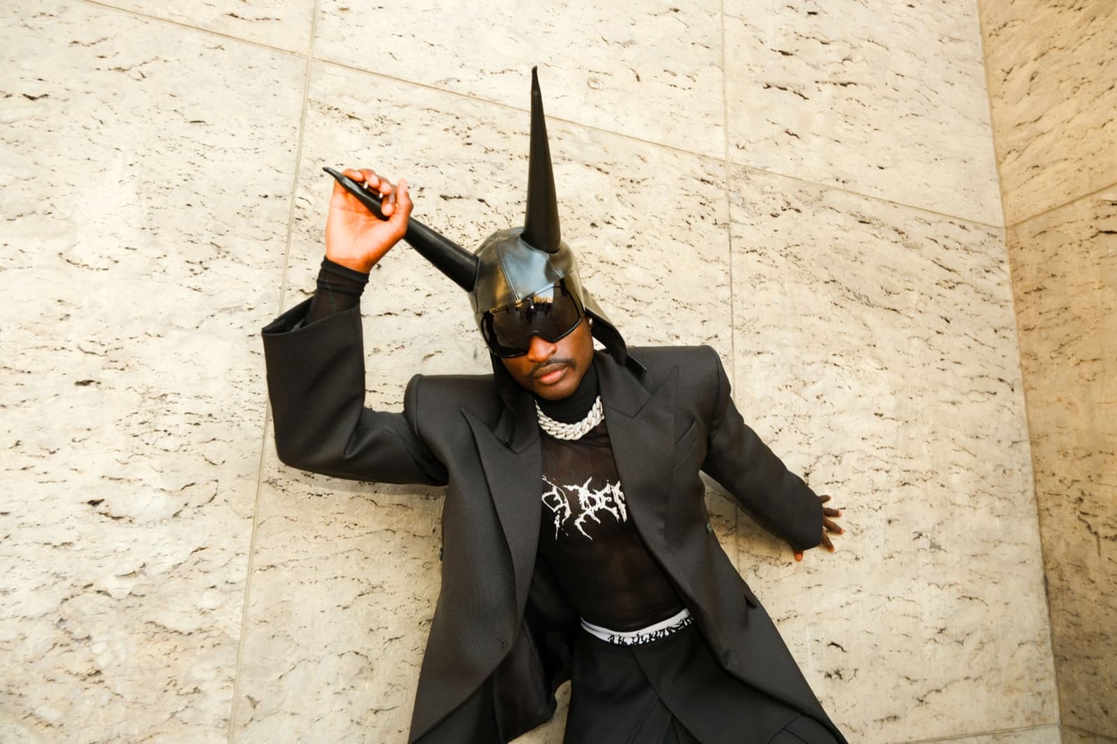 Avant-garde editorial portrait of a man in an oversized suit against a stone wall in Paris by SabShots