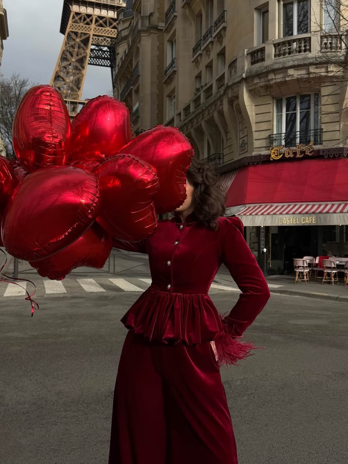 Woman in red velvet holding heart balloons by a Paris cafe near the Eiffel Tower, lifestyle photography by SabShots