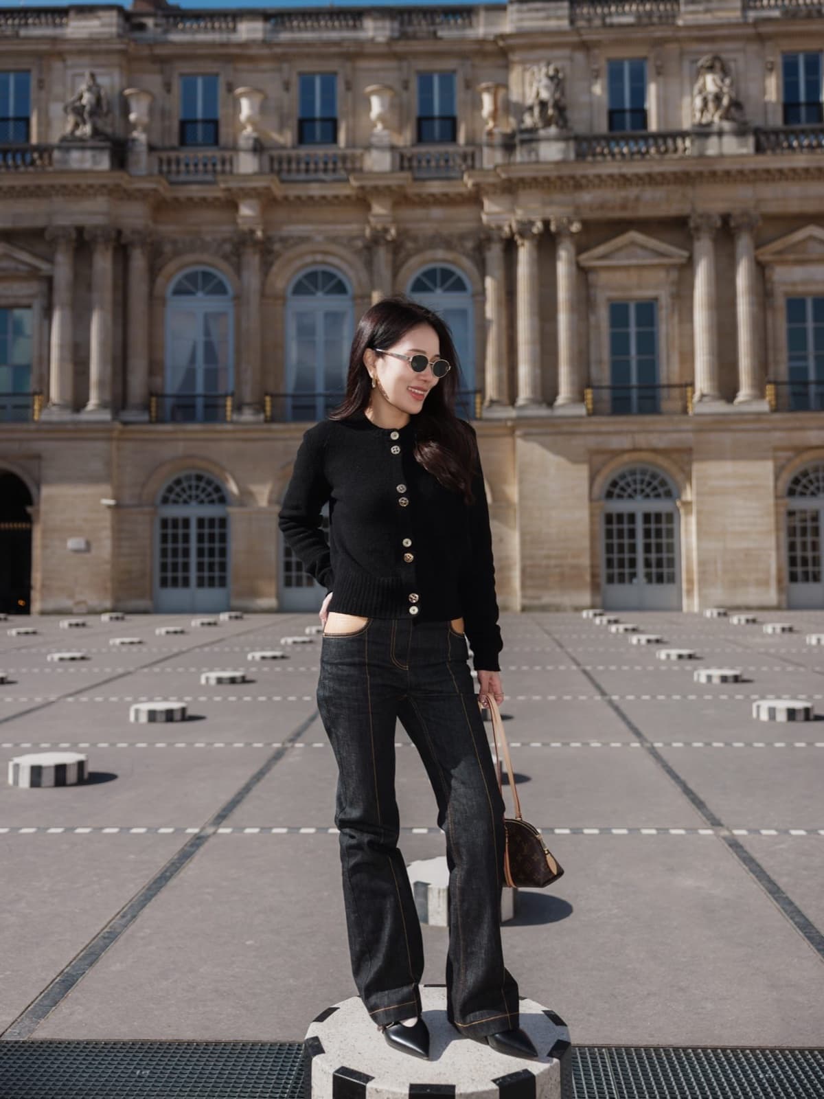 Woman in a black cardigan and sunglasses on the Buren columns at Palais-Royal in Paris by SabShots
