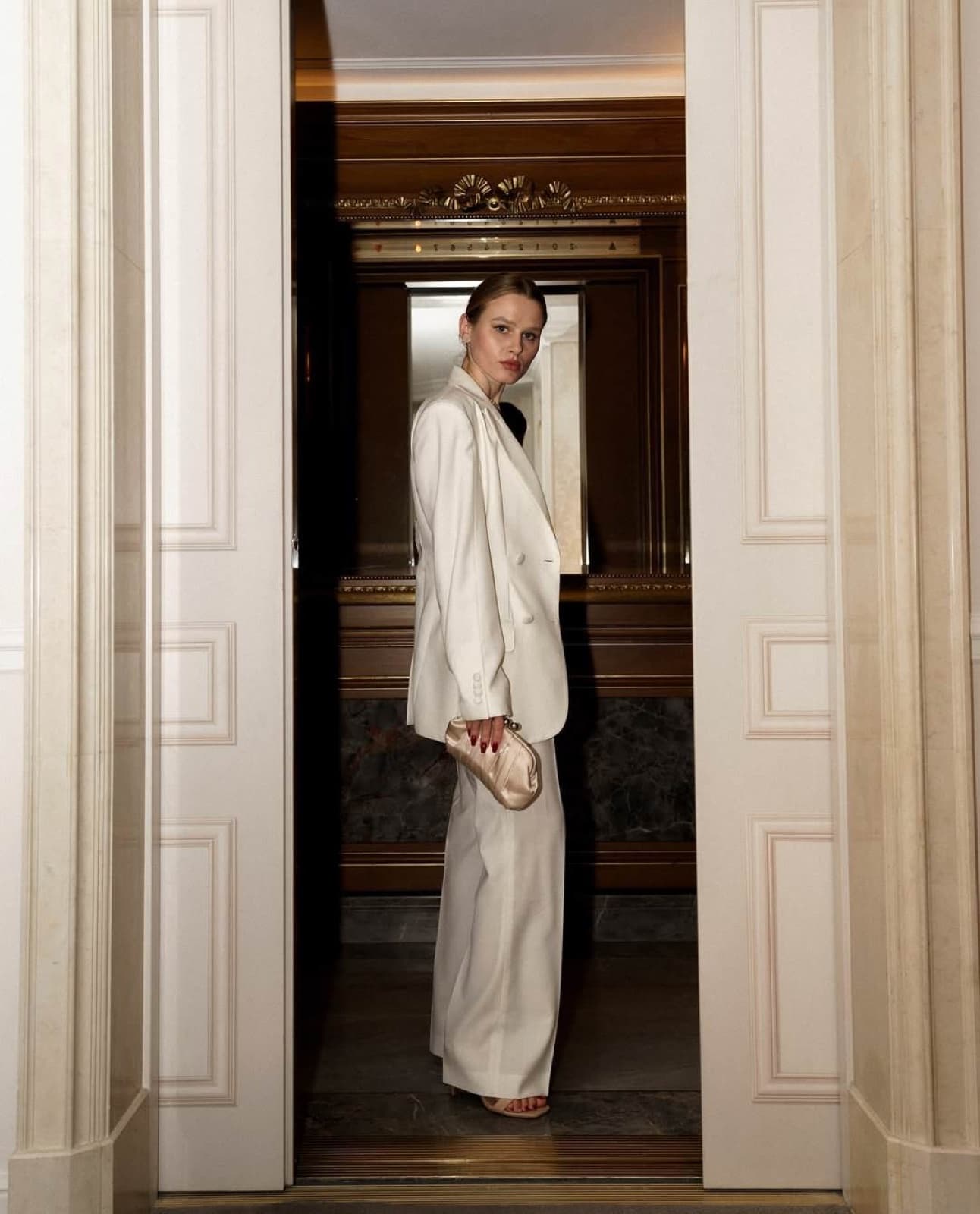 Woman in a cream suit in an ornate Parisian doorway, elegant editorial lifestyle portrait by SabShots