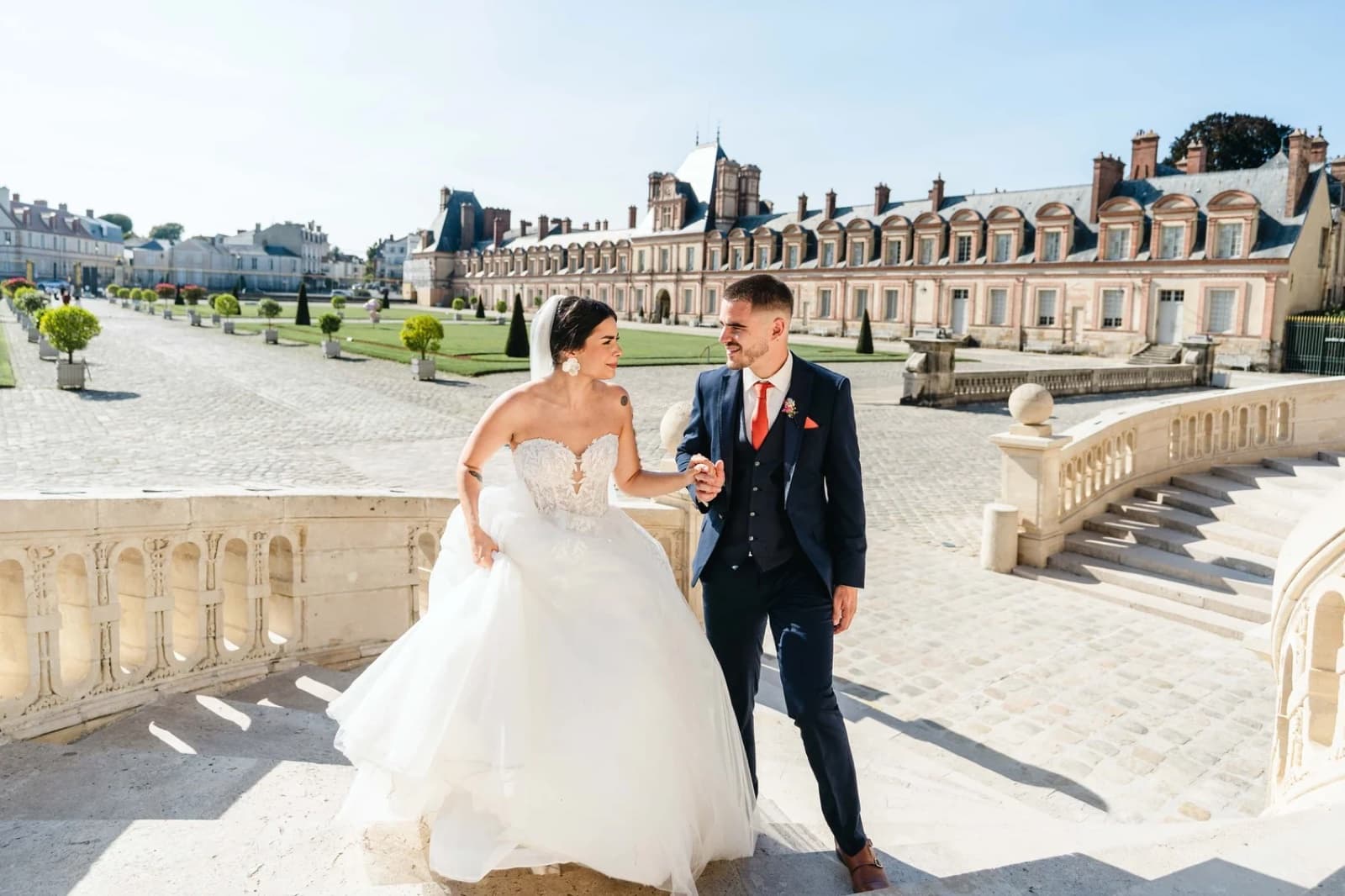 Bride and groom on a grand chateau staircase during their Paris wedding by SabShots