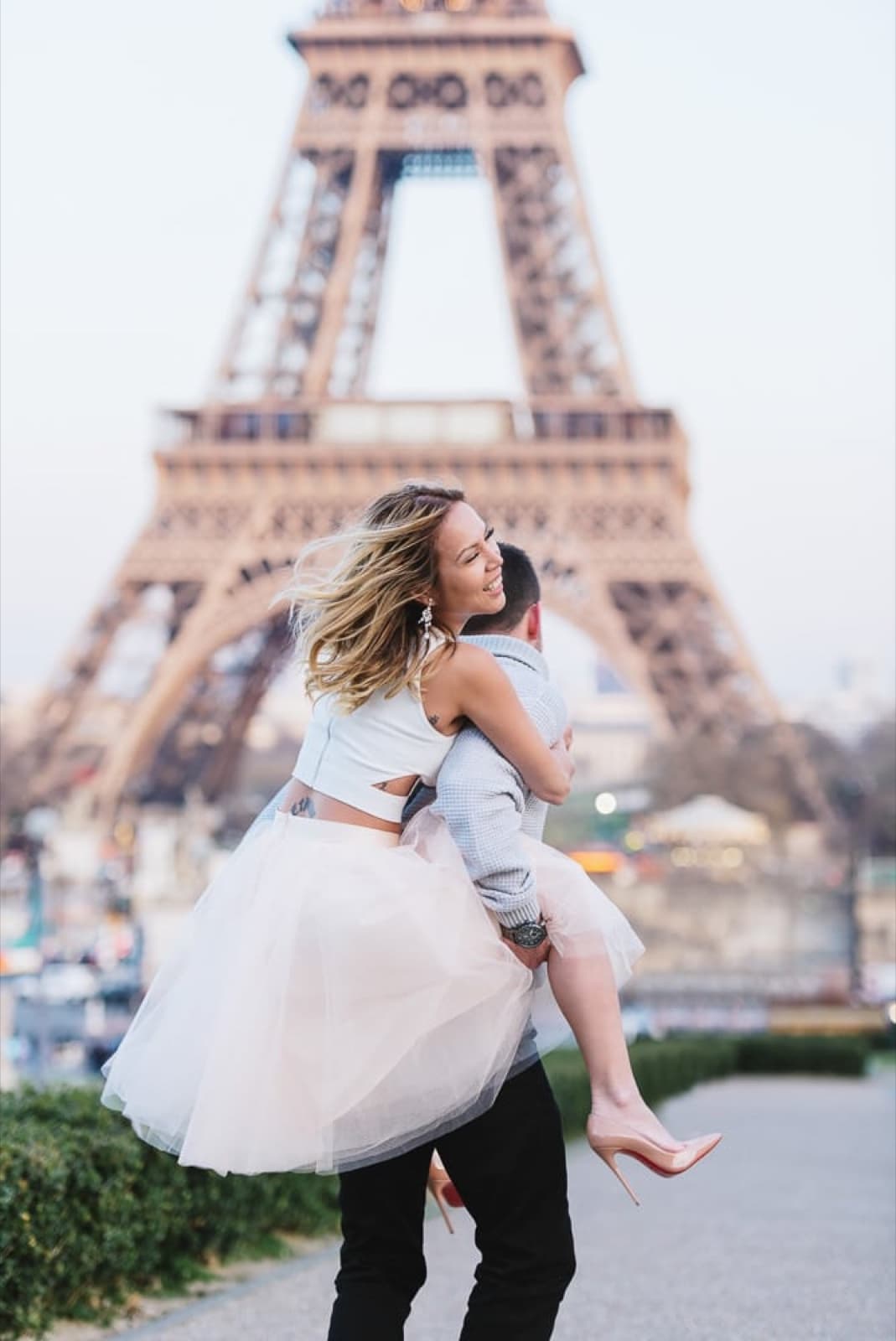 Groom carrying his bride in a flowing tutu dress in front of the Eiffel Tower in Paris by SabShots