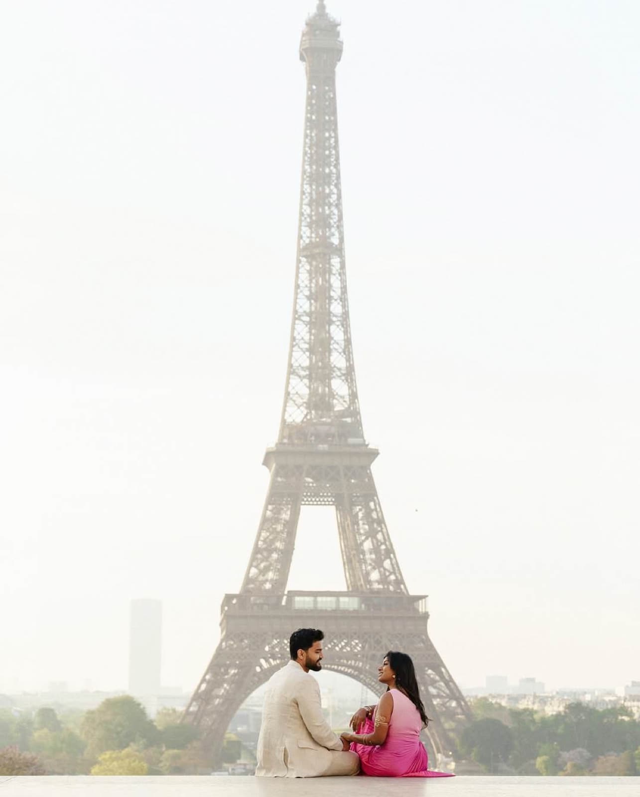 Loving couple seated against a soft view of the full Eiffel Tower at Trocadero in Paris by SabShots