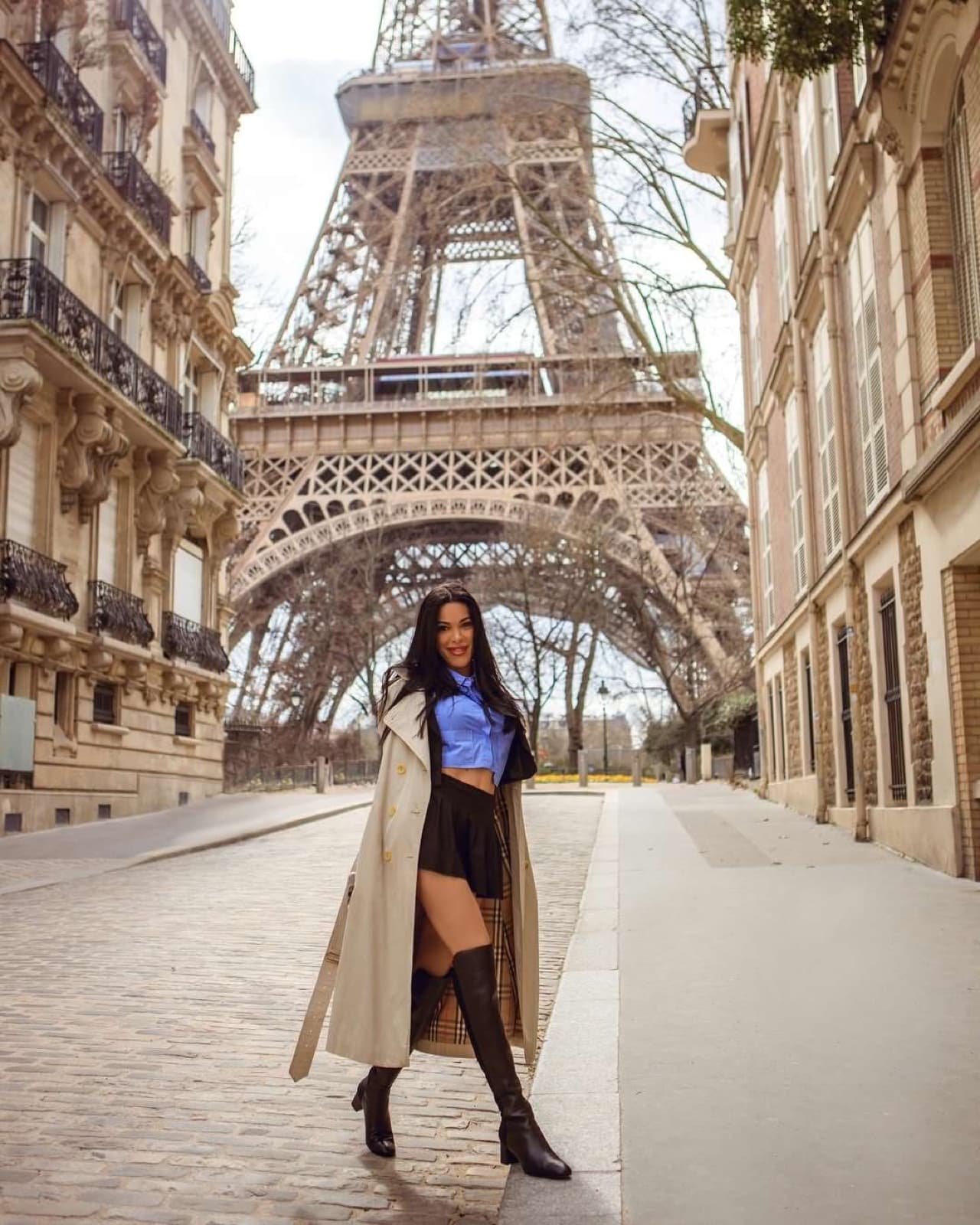 Stylish woman in a trench coat on a quiet cobbled street leading to the Eiffel Tower in Paris by SabShots