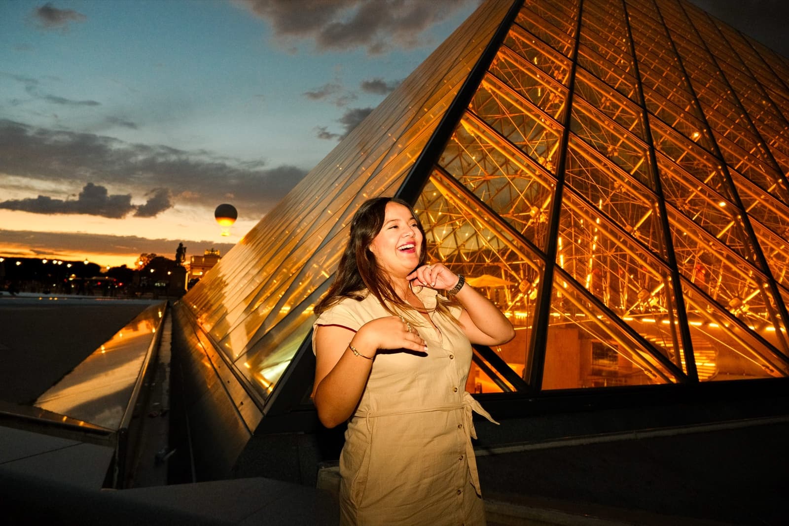 Woman beside the glowing Louvre Pyramid at golden sunset, an aesthetic instagrammable Paris photo spot by SabShots