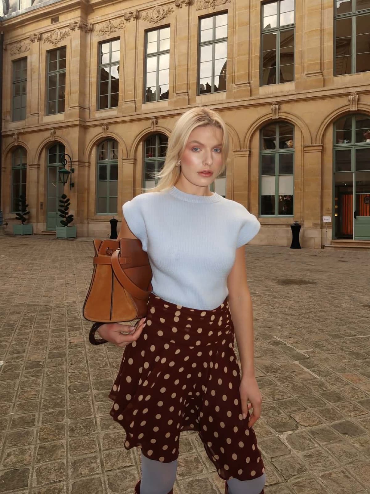 Woman in a polka-dot skirt in a historic Parisian courtyard, a chic instagrammable Paris look by SabShots