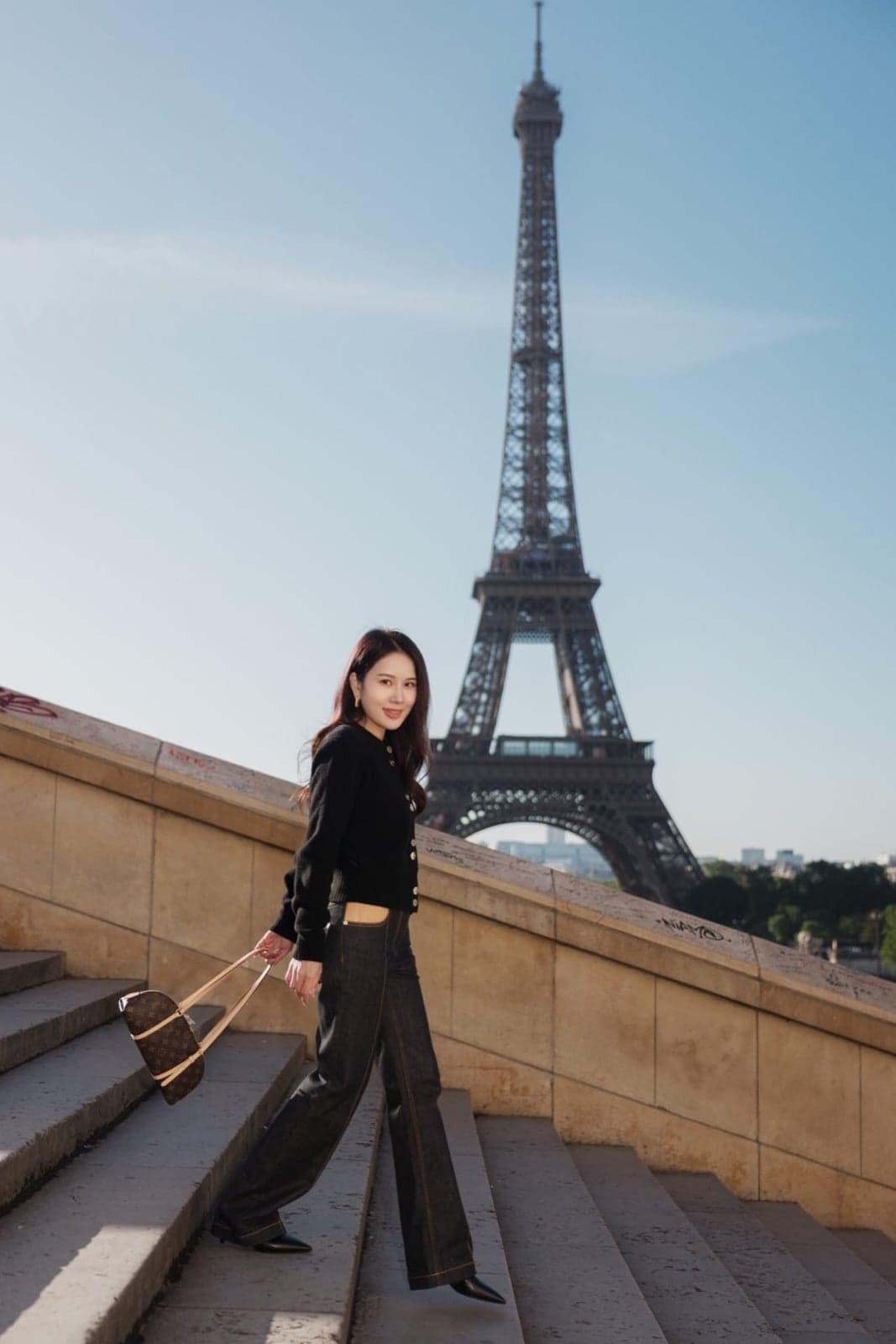 Chic woman walking the Trocadero steps with a clear morning view of the Eiffel Tower in Paris by SabShots