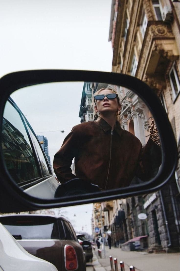 Blonde woman in a brown suede jacket reflected in a car mirror, Paris editorial street photography by SabShots
