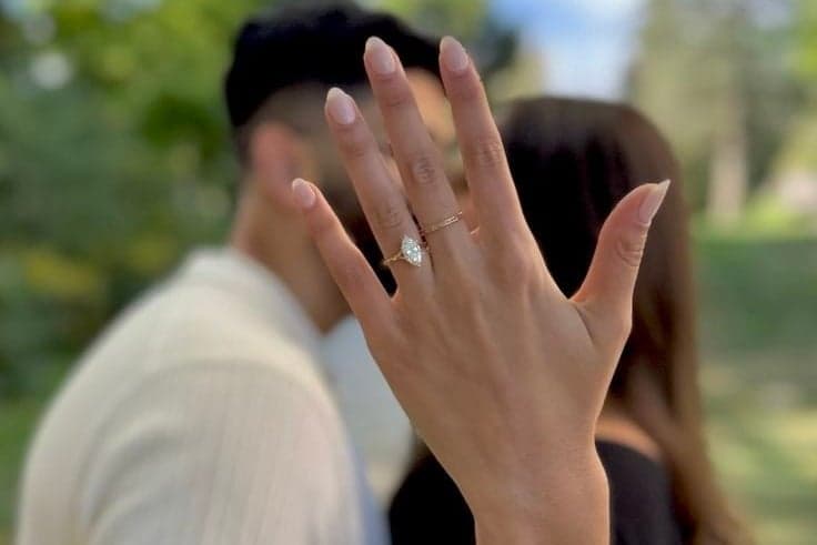 Woman showing her new diamond ring while kissing her fiance, engagement photo session in Paris by SabShots