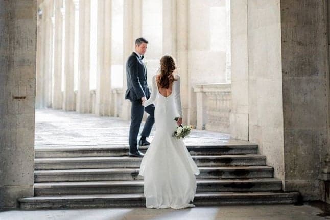 Groom leading his bride in a backless gown up colonnade steps, Paris wedding photography by SabShots