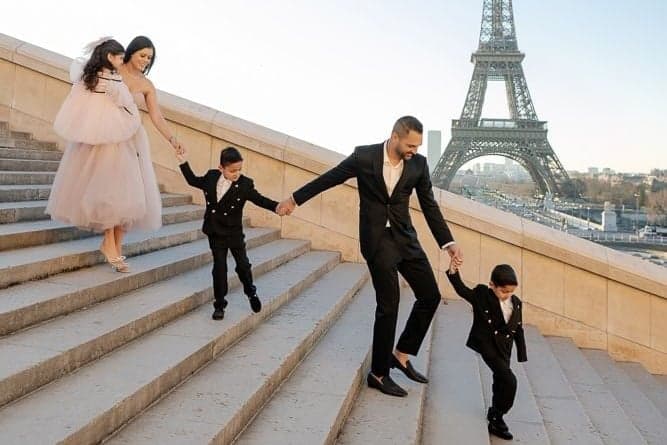 Family holding hands down the Trocadero steps with the Eiffel Tower behind, Paris family photo session by SabShots