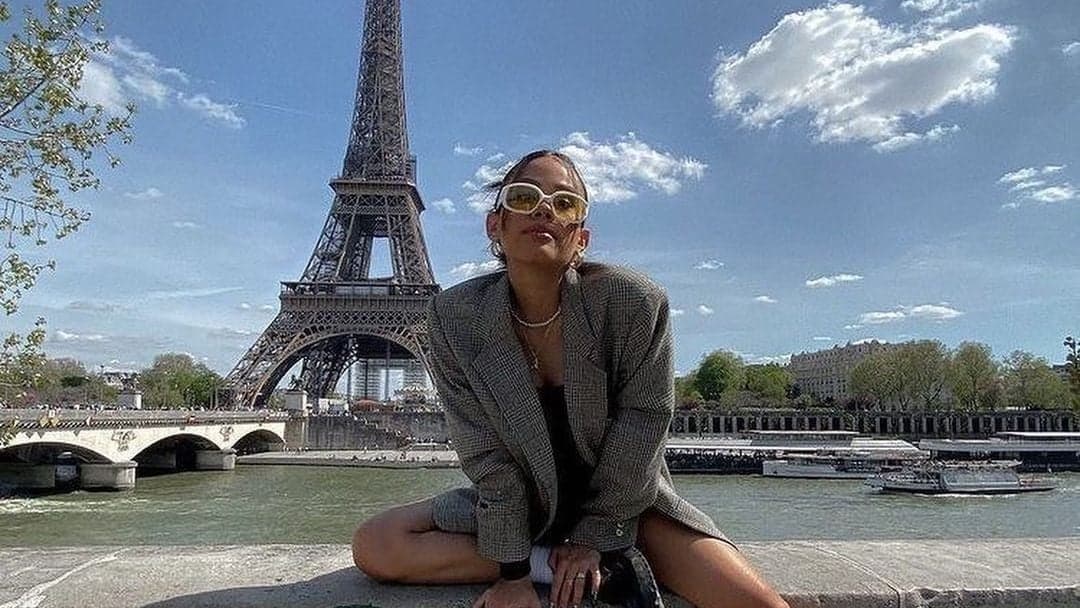 Woman in a checked blazer by the Seine with the Eiffel Tower under a blue Paris sky by SabShots