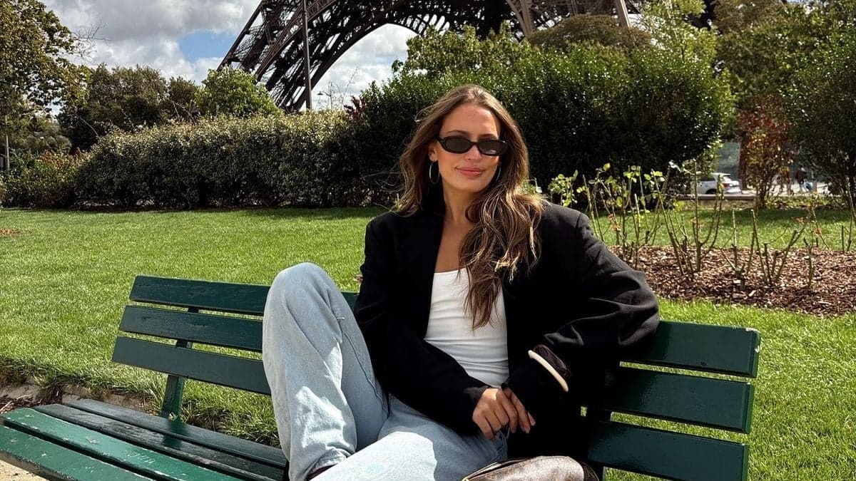 Woman in a black blazer on a green bench near the Eiffel Tower during her Paris session by SabShots