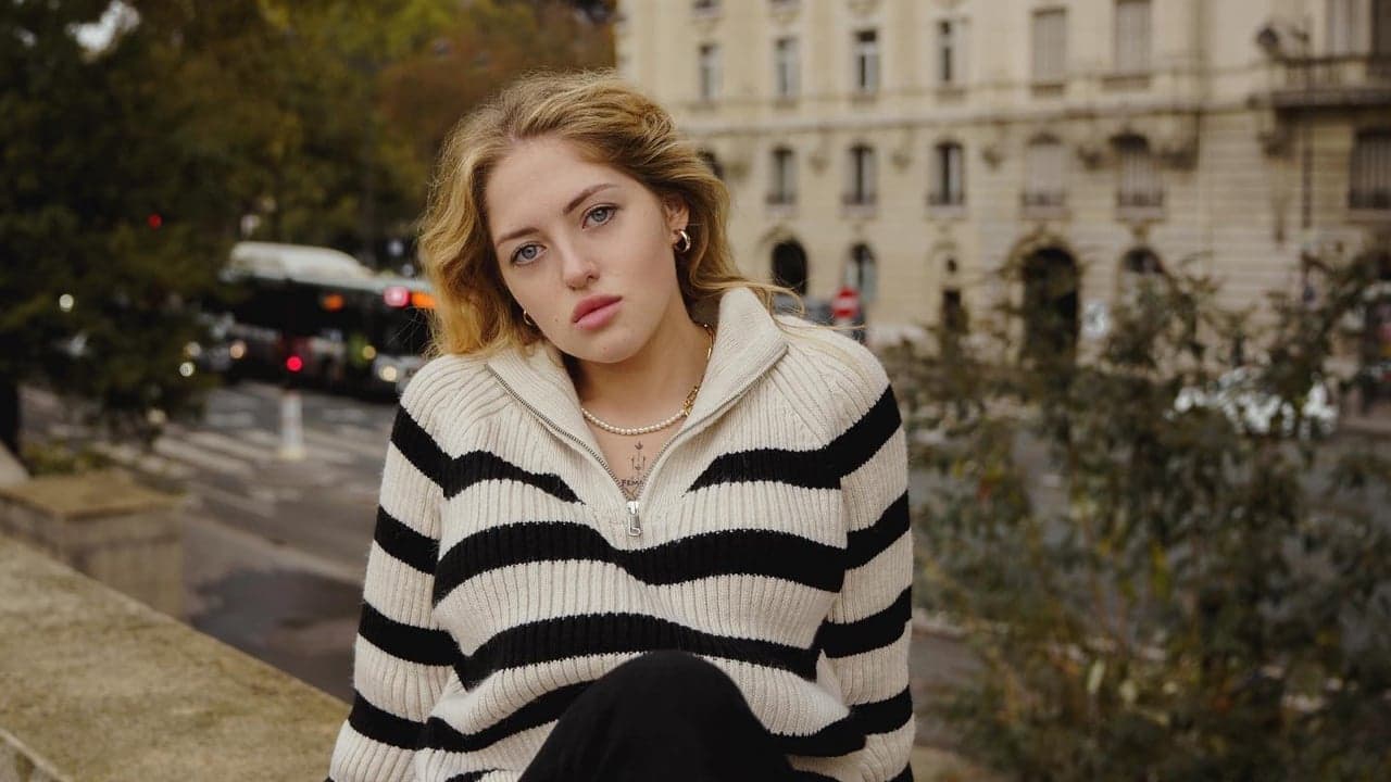 Woman in a striped sweater posing with the Eiffel Tower behind her during a solo photoshoot in Paris by SabShots