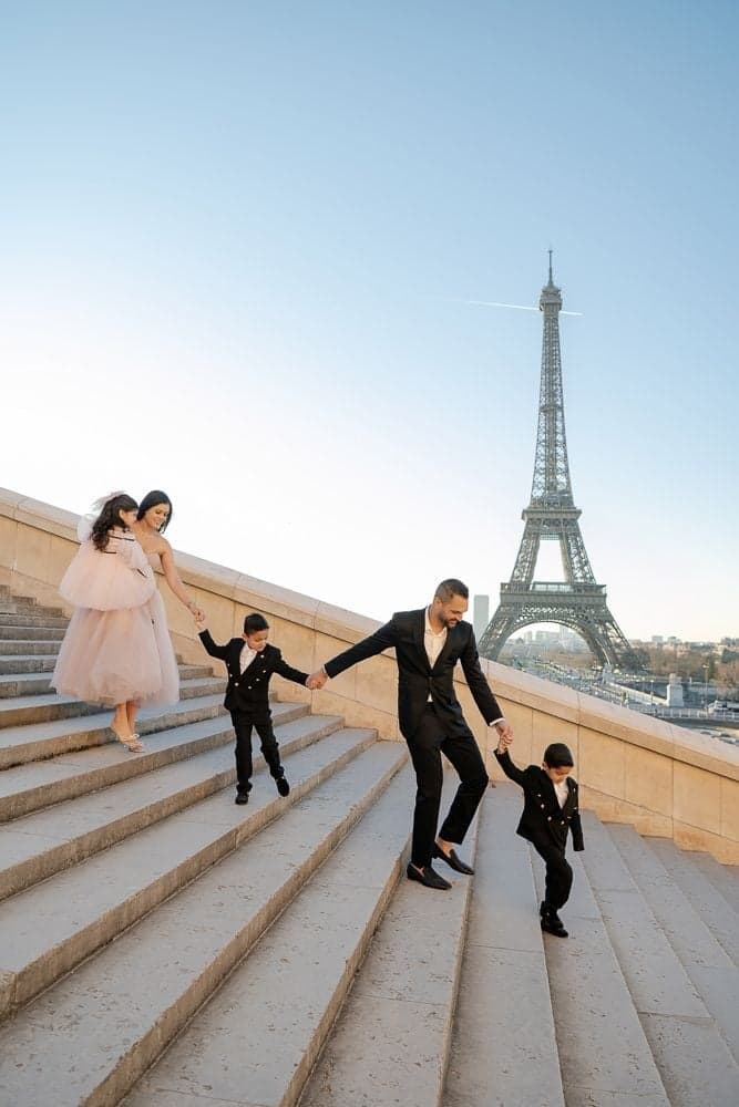 Dressed-up family of five descending the Trocadero stairs near the Eiffel Tower, Paris family portrait by SabShots