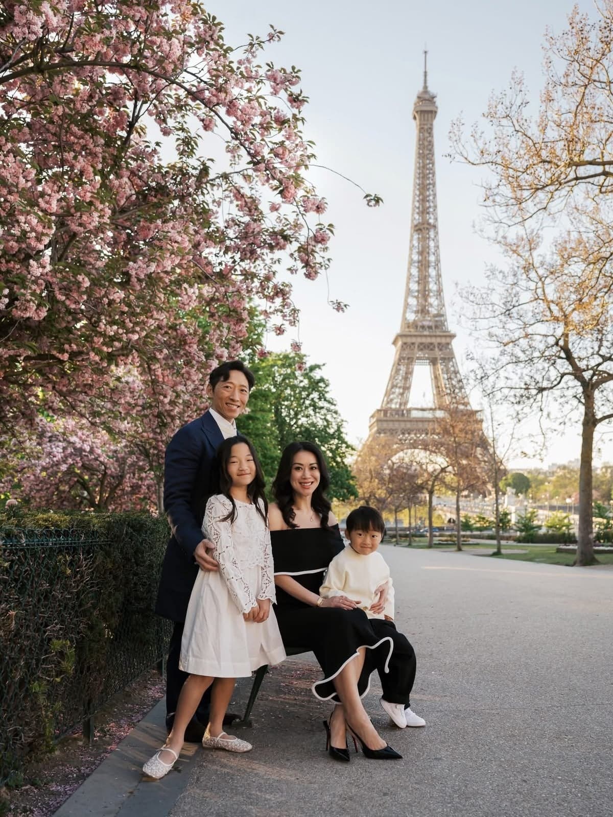 Parents and children posing under cherry blossoms near the Eiffel Tower, spring Paris family photo session by SabShots