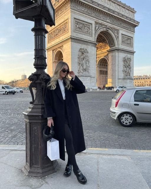 Woman in black leaning on a lamppost at the Arc de Triomphe, an instagrammable Paris moment by SabShots