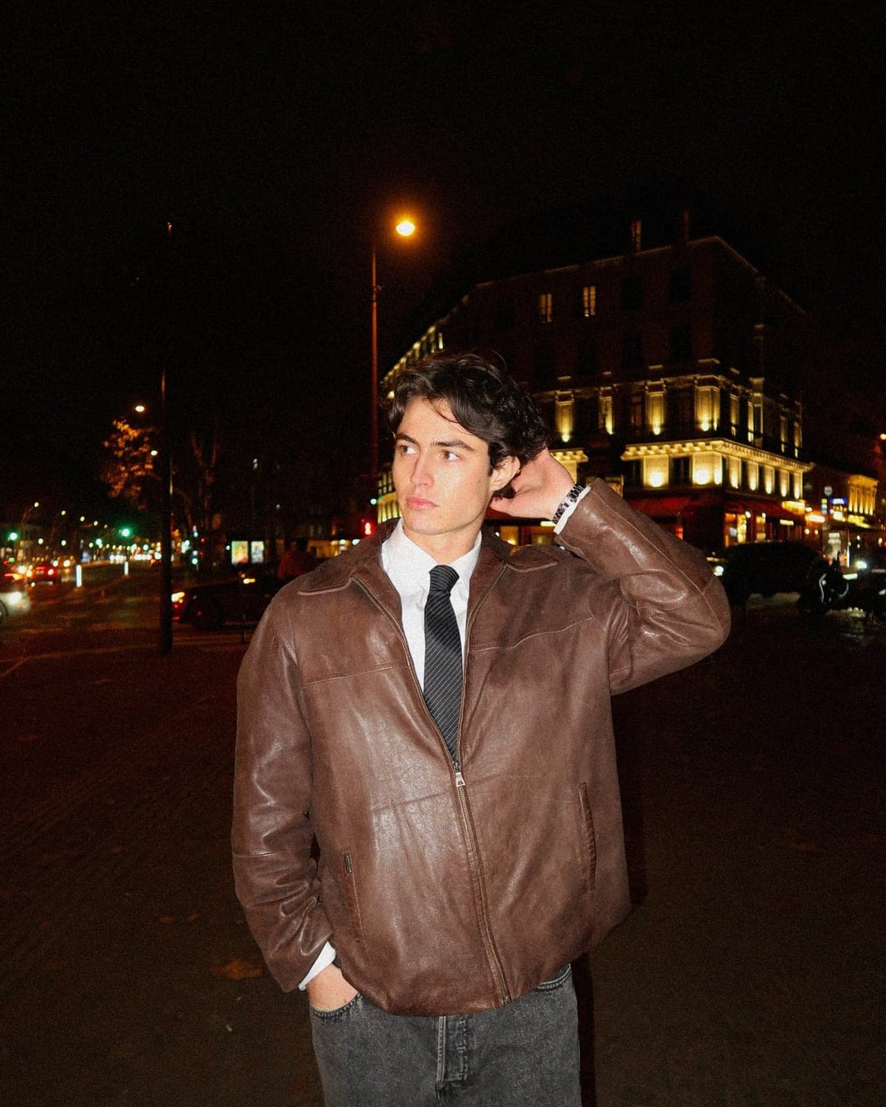 Man in a brown leather jacket and black tie under Paris streetlights, editorial street photography by SabShots