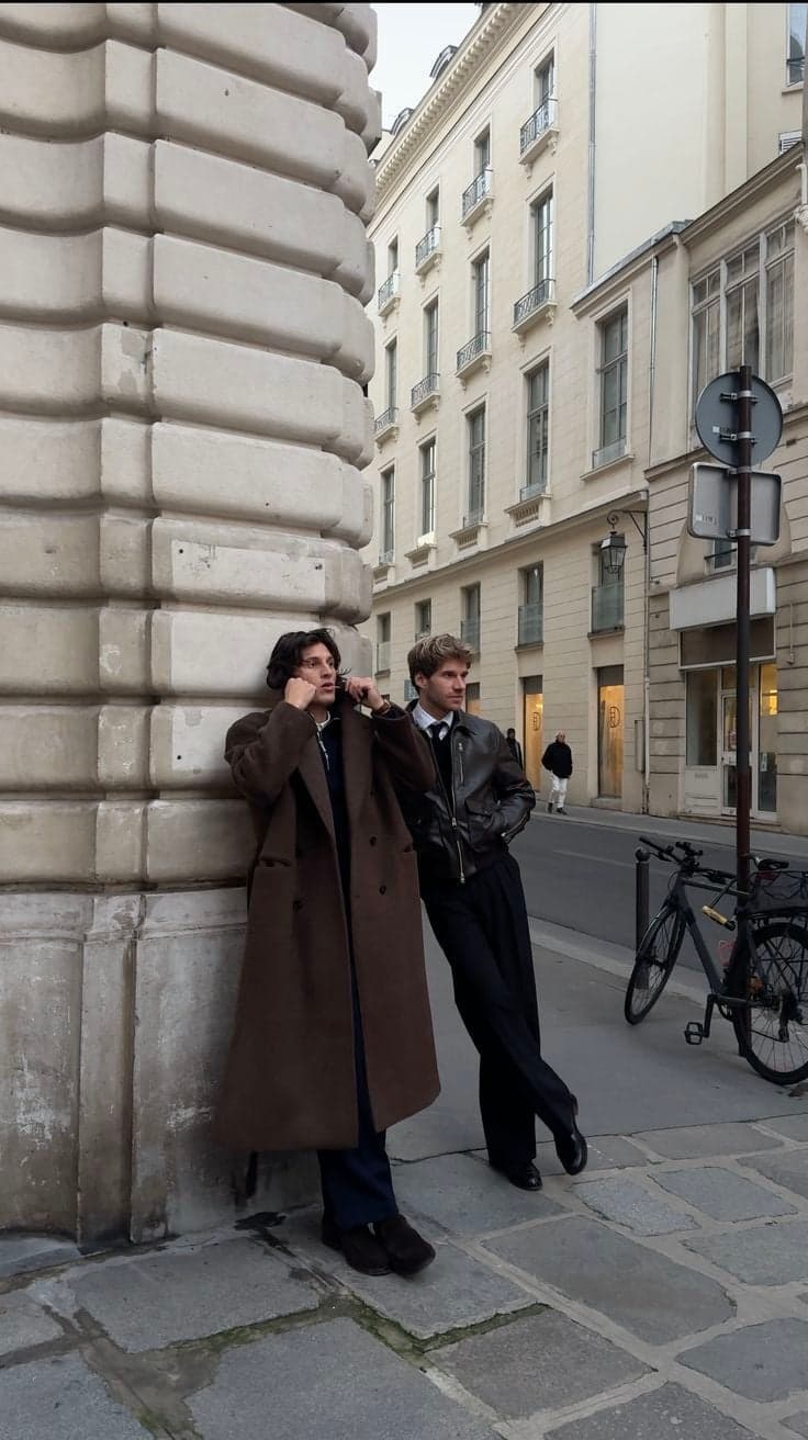 Two men in a brown overcoat and leather jacket on a Paris sidewalk, street style photography by SabShots