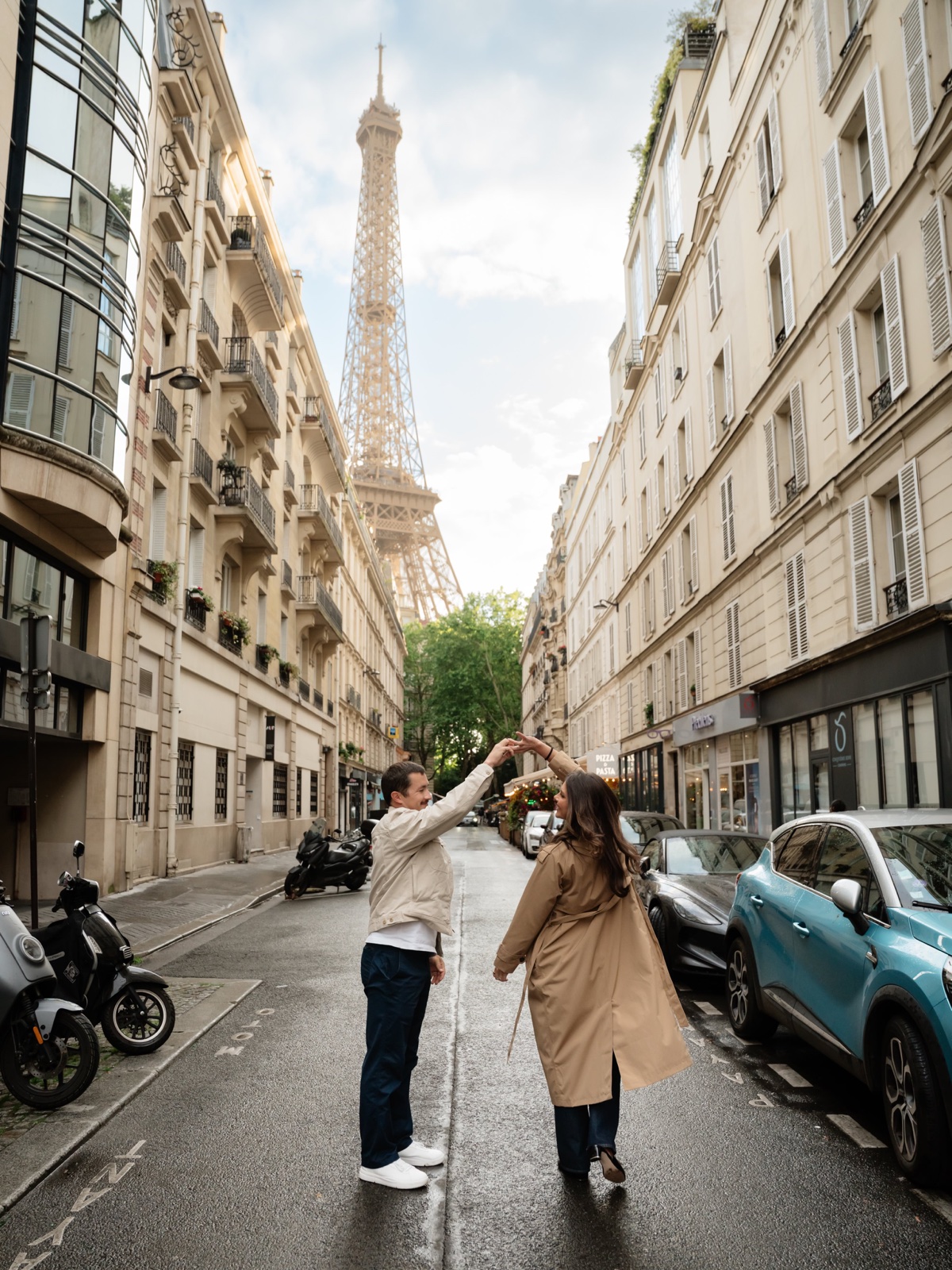 Couple twirling on a quiet Paris street with the Eiffel Tower behind them during a photo session by SabShots