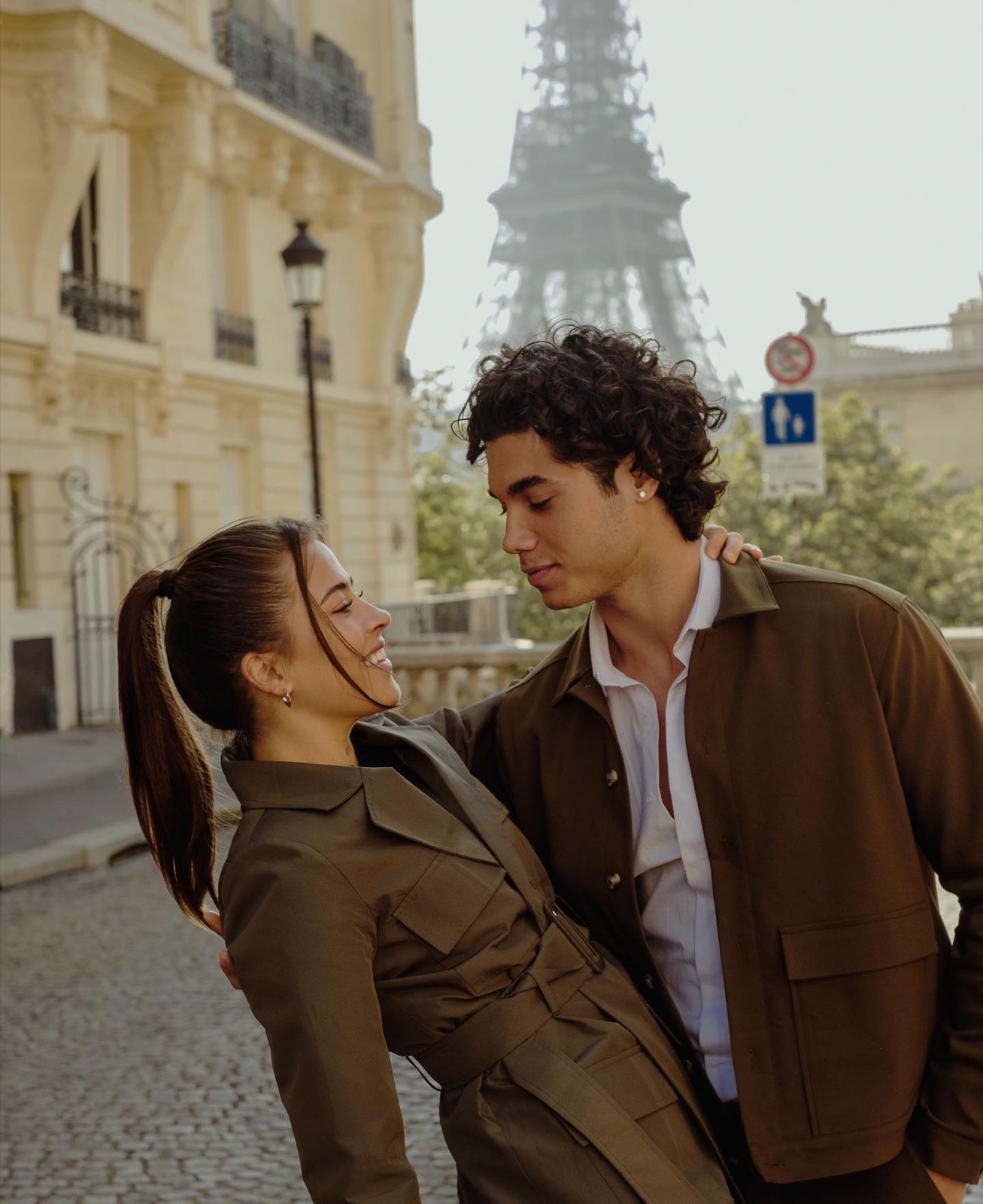 Couple in coordinated olive outfits on a Parisian street with the Eiffel Tower behind, styling for a Paris photoshoot by SabShots