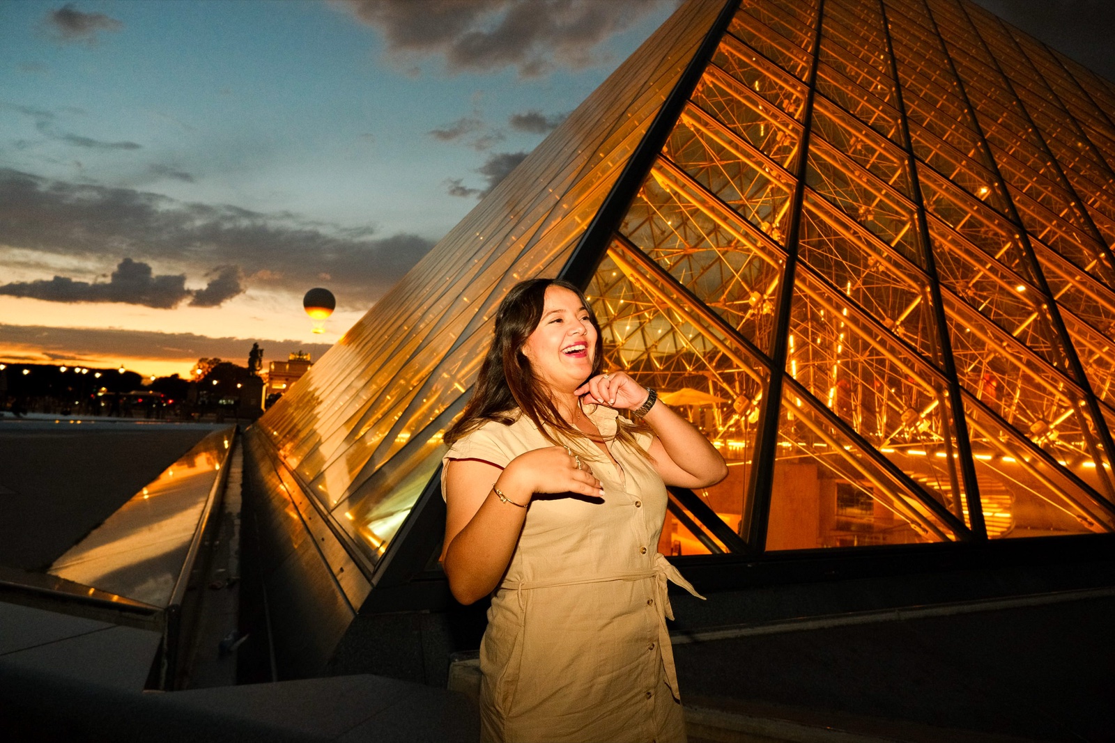 Woman beside the glowing Louvre Pyramid at golden sunset, an aesthetic instagrammable Paris photo spot by SabShots