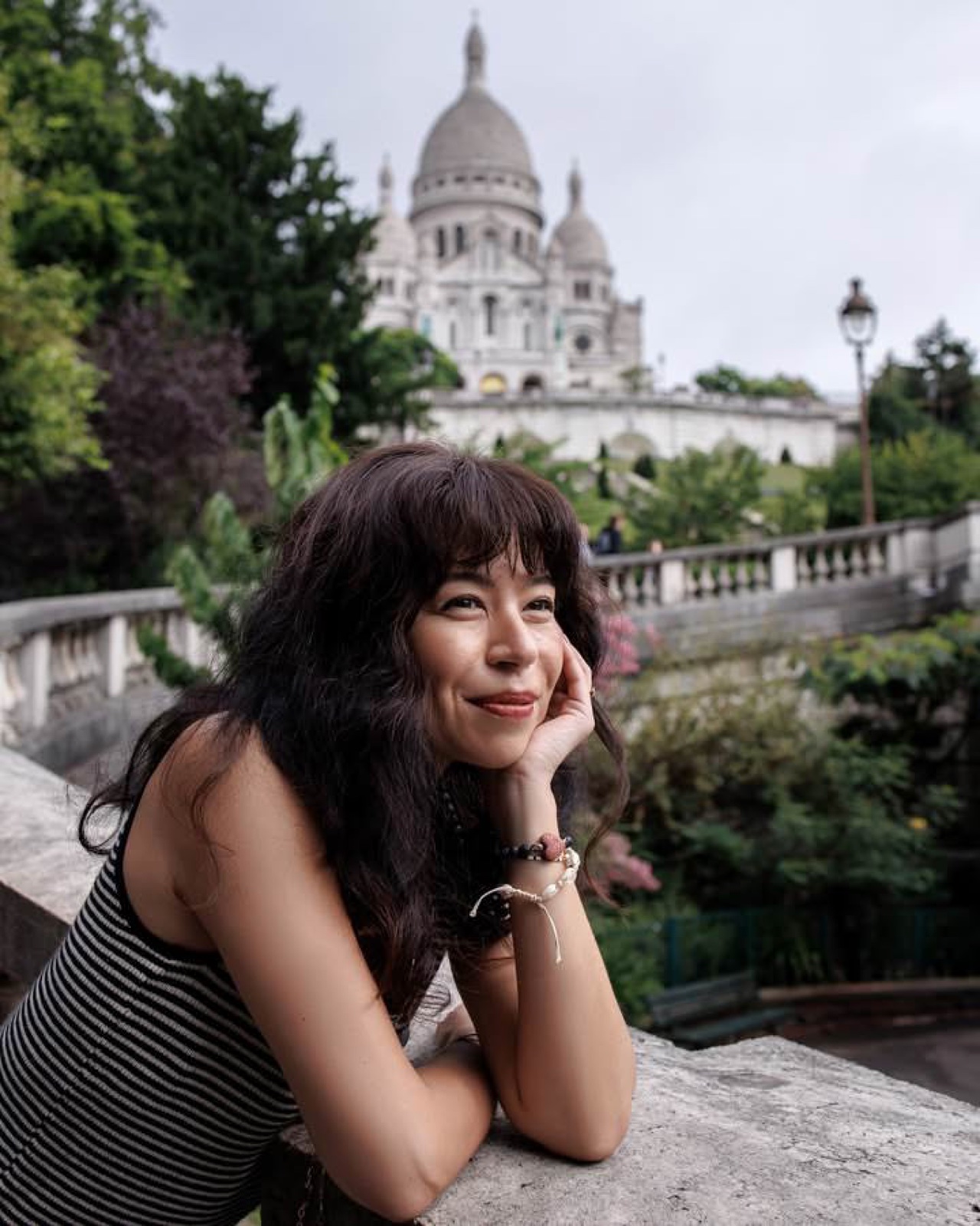 Woman smiling in front of the Sacre-Coeur basilica in Montmartre, a favorite Paris photo spot by SabShots