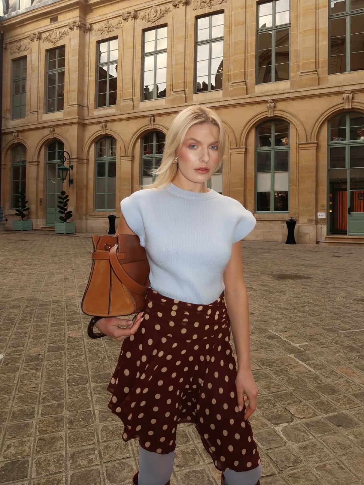 Woman in a polka-dot skirt in a historic Parisian courtyard, a chic instagrammable Paris look by SabShots